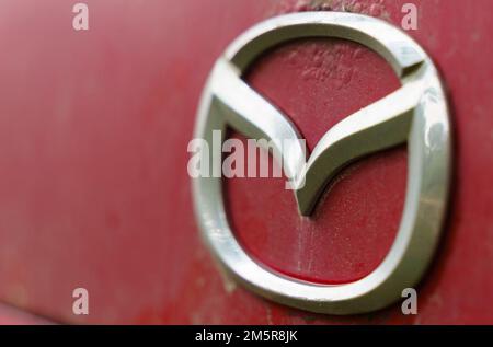 Bobruisk, Bielorussia, 27 luglio 2022: Primo piano del logo Mazda su un'auto dagli anni '90s. Foto Stock