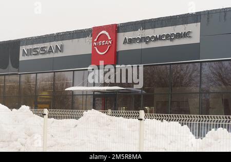 Bobruisk, Bielorussia, 17 dicembre 2022: Logo del marchio Nissan sulla parete della concessionaria, in inverno. Foto Stock