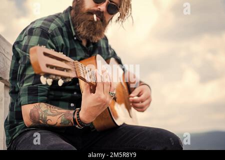 uomo barbuto in maglia a scacchi cantare canzone. musicista musicista musicista. strumento di stringa musicale. chitarrista maschile carismatico maturo. ragazzo con barba e. Foto Stock