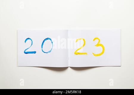 2023 dipinta con pitture giallo-blu come colore della bandiera dell'Ucraina su un album bianco su uno sfondo bianco, felice anno nuovo 2023 come un wallpape Foto Stock