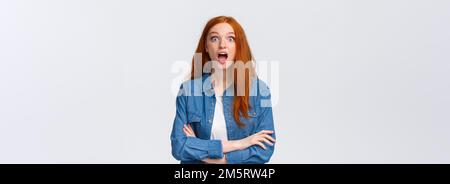 OMG, niente, incredibile. Impressionato e sorpreso, curiosa ragazza redhead cadere mascella dallo stupore, perdere il discorso, stellato stupito, in piedi Foto Stock