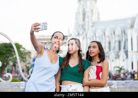 Turisti che prendono un selfie al Ponte di Ortiz con la chiesa la Ermita sullo sfondo nella città di Cali in Colombia Foto Stock