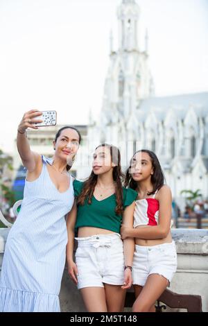 Turisti che prendono un selfie al Ponte di Ortiz con la chiesa la Ermita sullo sfondo nella città di Cali in Colombia Foto Stock