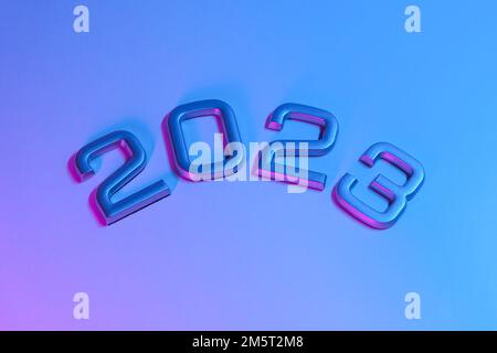 I numeri 2023 in luce al neon. Capodanno 2023 su sfondo rosa blu. La cartolina è in viola. Buon Natale. Foto Stock