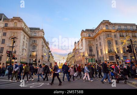 Persone che attraversano la strada a Piccadilly Circus a Londra, Regno Unito. Vista serale a sud da Piccadilly Circus verso Regent Street Saint James's. Foto Stock