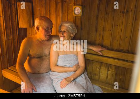 Anziano pensionato uomo e donna rilassarsi insieme nella sauna in legno spa. Foto di alta qualità Foto Stock