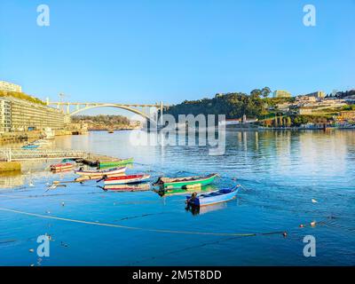 Barche ormeggiate pescatori, terrapieno serale soleggiato, vista sul ponte di Arrabida, Porto, Portogallo Foto Stock