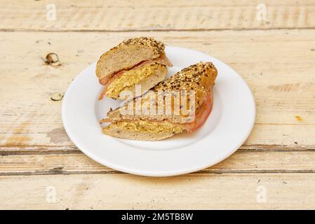 Sandwich di pane baguette con semi farciti in una tortilla con fettine di pollo e pomodoro Foto Stock