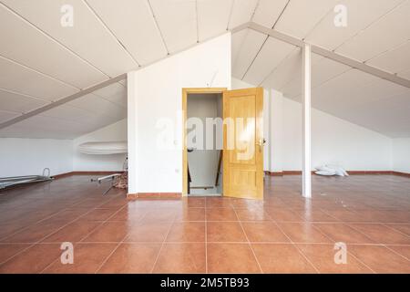 Una grande sala vuota di una casa indipendente in mansarda mansardata con accesso con una porta di quercia per le scale di cambiare livello Foto Stock