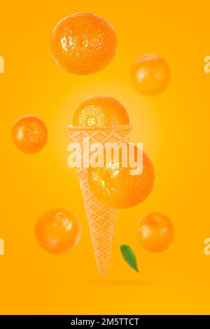 Cono di gelato cadente con frutti di mandarino. Sette tangerini interi volanti su un tavolo colorato con percorso di ritaglio come elemento di design della confezione e pubblicità Foto Stock