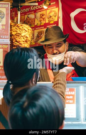 Uomo mediorientale che serve i clienti in uno stand kebab Foto Stock