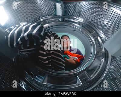 La lavatrice è caricata con i vestiti sporchi da un uomo Foto Stock