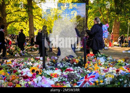 Una silhouette di vetro e tributi floreali con i lutto visitano Green Park dopo la morte della Regina Elisabetta II, Londra, Regno Unito Foto Stock