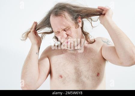 L'uomo arrabbiato per i suoi lunghi capelli Foto Stock