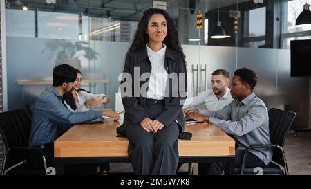 Donna d'affari sorridente e penosa capo donna donna donna donna seduto sul tavolo in ufficio pensare. Dipendenti multirazziali lavoratori multietnici colleghi in Foto Stock