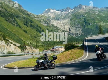 Traffico sulla strada di passaggio per il Passo Furka vicino a Gletsch, sullo sfondo le acque di testa del Rodano nel ghiaccio-free ripido ex morena di terra Foto Stock