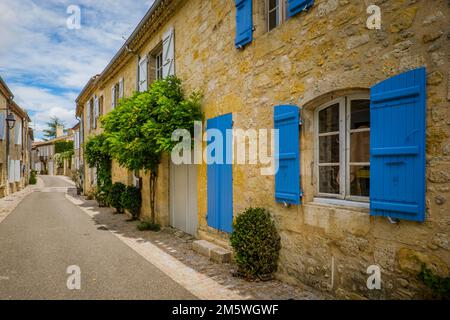 Facciate pittoresche e fiorite di case con persiane e porte in legno colorato nel villaggio di Terraube nel sud della Francia (Gers) Foto Stock