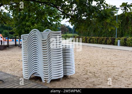 Dopo la stagione estiva, i lettini sulla spiaggia della città si stackano accanto allo stagno. La fine dell'attività ricreativa all'inizio dell'autunno Foto Stock