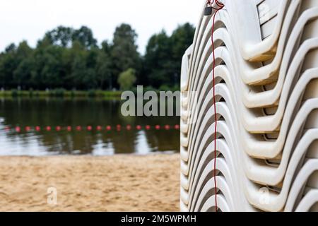 Dopo la stagione estiva, i lettini sulla spiaggia della città si stackano accanto allo stagno. La fine dell'attività ricreativa all'inizio dell'autunno Foto Stock