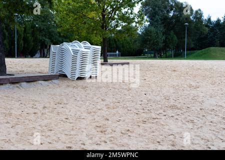 Dopo la stagione estiva, i lettini sulla spiaggia della città si stackano accanto allo stagno. La fine dell'attività ricreativa all'inizio dell'autunno Foto Stock