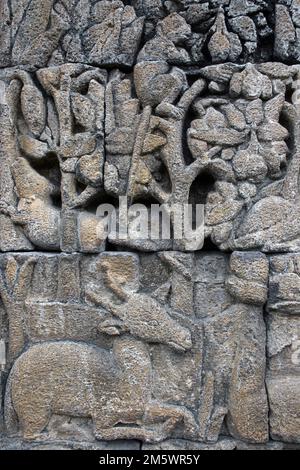 Cervo in pietra sotto Un albero con scimmia - Tempio di Borobudur, Giava Foto Stock