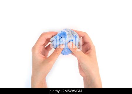 Gioco a mano con texture slime su sfondo bianco. Mano teen che tiene blu brillante slime con bolle, stretching la sostanza gooey. Ragazza adolescente Foto Stock