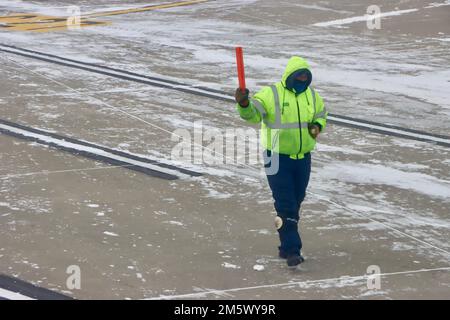 Solitario lavoratore aeroportuale su asfalto su Cleveland Hopkins aeroporto la vigilia di Natale 2022 dopo la tempesta di neve. Foto Stock