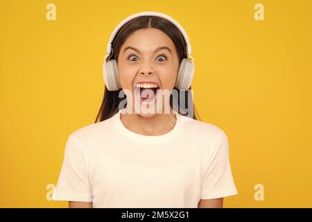 Bambini entusiasti che ascoltano musica con le cuffie. Ragazza che ascolta i brani tramite auricolari wireless. Accessorio per dispositivo auricolare. Ragazza adolescente alla moda Foto Stock