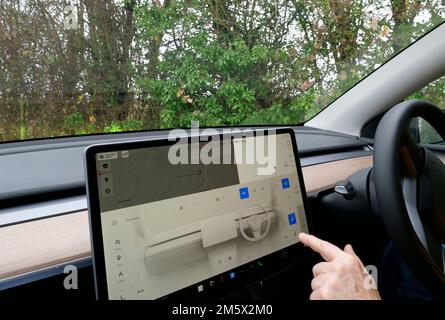 Display di bordo dell'auto elettrica. Veicolo elettrico Tesla con guida a destra e cruscotto con display a bordo Foto Stock