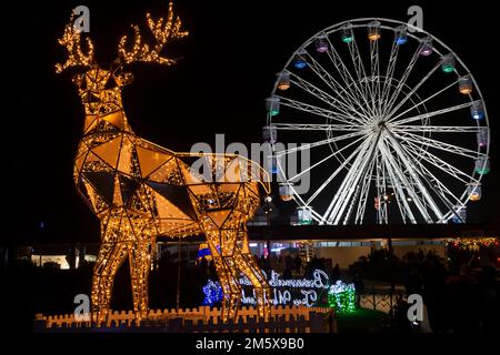 Christmas Tree Wonderland, Bournemouth, Dorset UK a dicembre - scintillanti ornamenti di renne con grande ruota dietro al Pier Approach Foto Stock