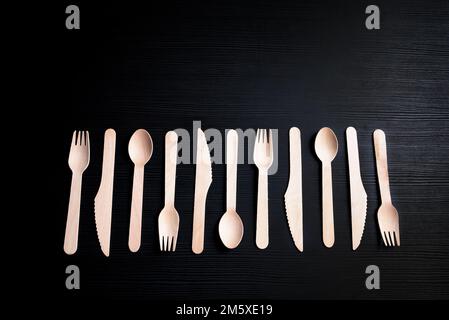 cucchiai, forchette e coltelli in legno ecologici monouso su sfondo scuro Foto Stock