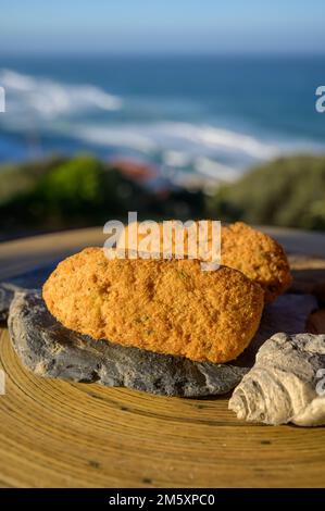 Coccodrillo pastais de bacalhau, spuntini tradizionali portoghesi serviti all'aperto con vista sull'oceano Atlantico blu vicino a Sintra nella zona di Lisbona, P Foto Stock