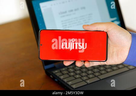 Logo di Fujitsu Cloud su uno smartphone davanti a un computer. Fujitsu Cloud è un servizio di tecnologia per il cloud computing di Fujitsu. Foto Stock