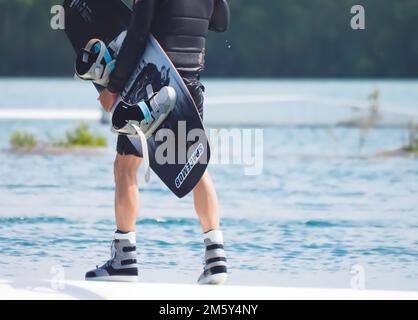 Il wakeboarder uomo porta la sua tavola Foto Stock