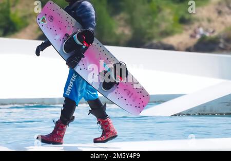 Il wakeboarder uomo porta la sua tavola Foto Stock