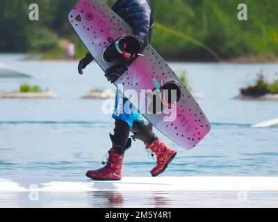 Il wakeboarder uomo porta la sua tavola Foto Stock