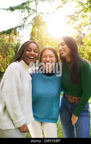 Verticale Ritratto di tre ragazze all'esterno guardando la fotocamera. Amici gruppi multietnici di persone Foto Stock