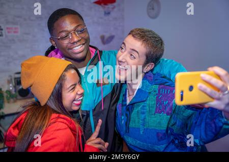Amici adolescenti multietnici che scattano foto selfie con flash non filtrato. Riprese notturne in interni. Foto Stock