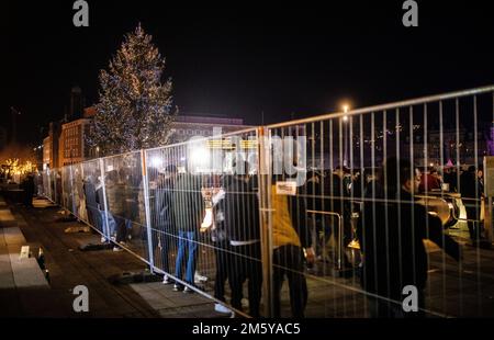 Stoccarda, Germania. 31st Dec, 2022. La gente si trova accanto a una recinzione a Schlossplatz, presso il cordoned-off Königsbau. I fuochi d'artificio sono vietati nell'anello della città di Stoccarda la vigilia di Capodanno - la città ha organizzato una festa di Capodanno sulla Schlossplatz. Ci sono controlli agli ingressi dell'area festeggiamenti, perché secondo l'organizzatore i pirocerrimi e la presa del vetro non sono ammessi per motivi di sicurezza. Credit: Christoph Schmidt/dpa/Alamy Live News Foto Stock