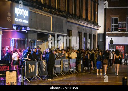 Wardwick, Derby, 31 dicembre 2022. Si sono formate enormi code nei nightclub, con alcuni festaioli che non sono riusciti ad entrare prima di mezzanotte a Derby. Il moomoo del club aveva la fila più grande che si estendeva intorno all'isolato. I rivelatori usavano cappotti per ripararsi dalla pioggia mentre camminavano tra i club da Wardwick a Friar Gate nel centro di Derby a pochi minuti da mezzanotte. Migliaia di festaioli hanno riempito i bar e i club mentre i festeggiamenti continuavano fino al nuovo anno. Credito: Interrompi stampa Media/Alamy Live News Foto Stock