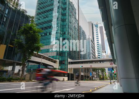 Strada e auto sul traffico che si spostano nel quartiere finanziario del centro con un grattacielo in mattinata a Singapore. Foto Stock