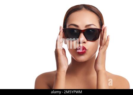 Bellezza con atteggiamento. Studio ritratto di una giovane donna che indossa occhiali da sole in posa su uno sfondo bianco. Foto Stock