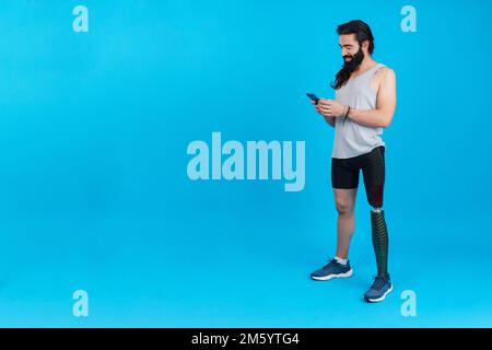 Uomo sportivo con protesi della gamba che utilizza un dispositivo mobile Foto Stock