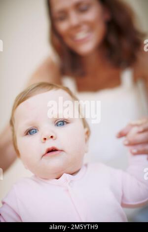 Non può aspettare di camminare da sola. Primo piano di una bambina aiutata da sua madre a prendere i suoi primi passi. Foto Stock