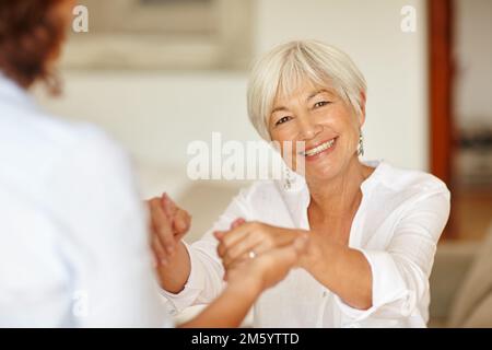 Mia figlia si prende cura di me. Ritratto di una donna anziana che tiene le mani delle figlie. Foto Stock