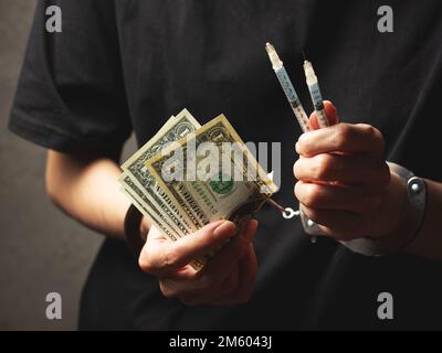 Manette su polsi, banconote e siringa Foto Stock