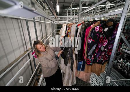 La stilista di moda Oxfam Bay Garnett al magazzino Oxfam di Milton Keynes mostra alcuni degli abiti che ha messo insieme per la London Fashion Week. Una sfilata di passerelle con oggetti di Oxfam sarà presente alla London Fashion Week a febbraio. Bay Garnett, che ha messo insieme i vestiti per la mostra di Oxfam, ha detto che fare shopping nei negozi di beneficenza è un modo sostenibile di godere della moda, e indossare abiti di seconda mano è diventato un atto di ribellione per i giovani preoccupati per il cambiamento climatico. Data immagine: Lunedì 5 dicembre 2022. Foto Stock