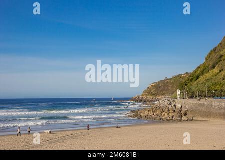 Persone che camminano sulla spiaggia di Zurriola a San Sebastian, Spagna Foto Stock