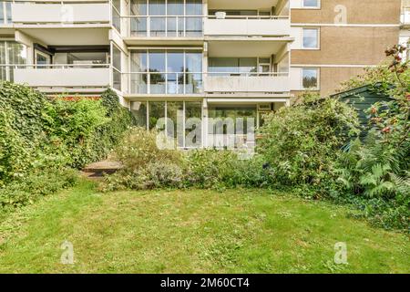 un edificio di appartamenti con molte piante nel cortile anteriore e prati su entrambi i lati dell'edificio sono lussureggianti erba verde Foto Stock