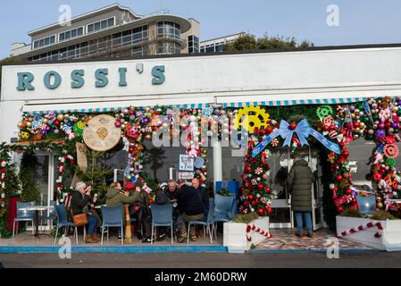 Western Esplanade, Southend on Sea, Essex, Regno Unito. 1st Jan, 2023. La gente è fuori a godersi il clima mite di Capodanno lungo il lungomare di Southend, con alcuni pasti fuori dalla gelateria Rossi con le sue colorate decorazioni natalizie Foto Stock